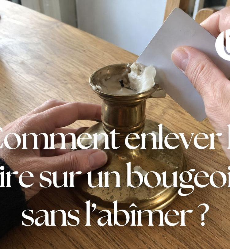 Des mains retirent délicatement de la cire blanche refroidie d’un bougeoir en laiton avec une carte en plastique.