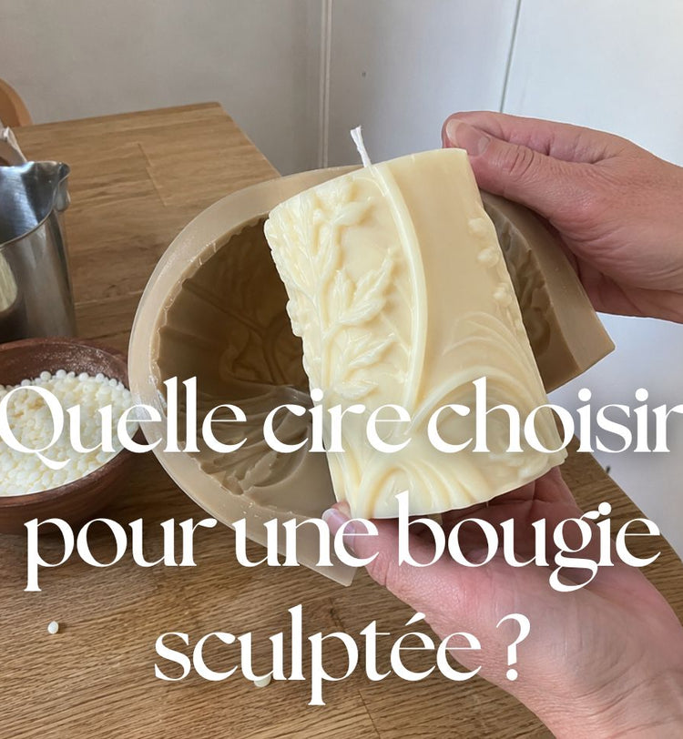 Démoulage d’une bougie sculptée en cire ivoire dans un moule en silicone, avec des pastilles de cire sur une table en bois.